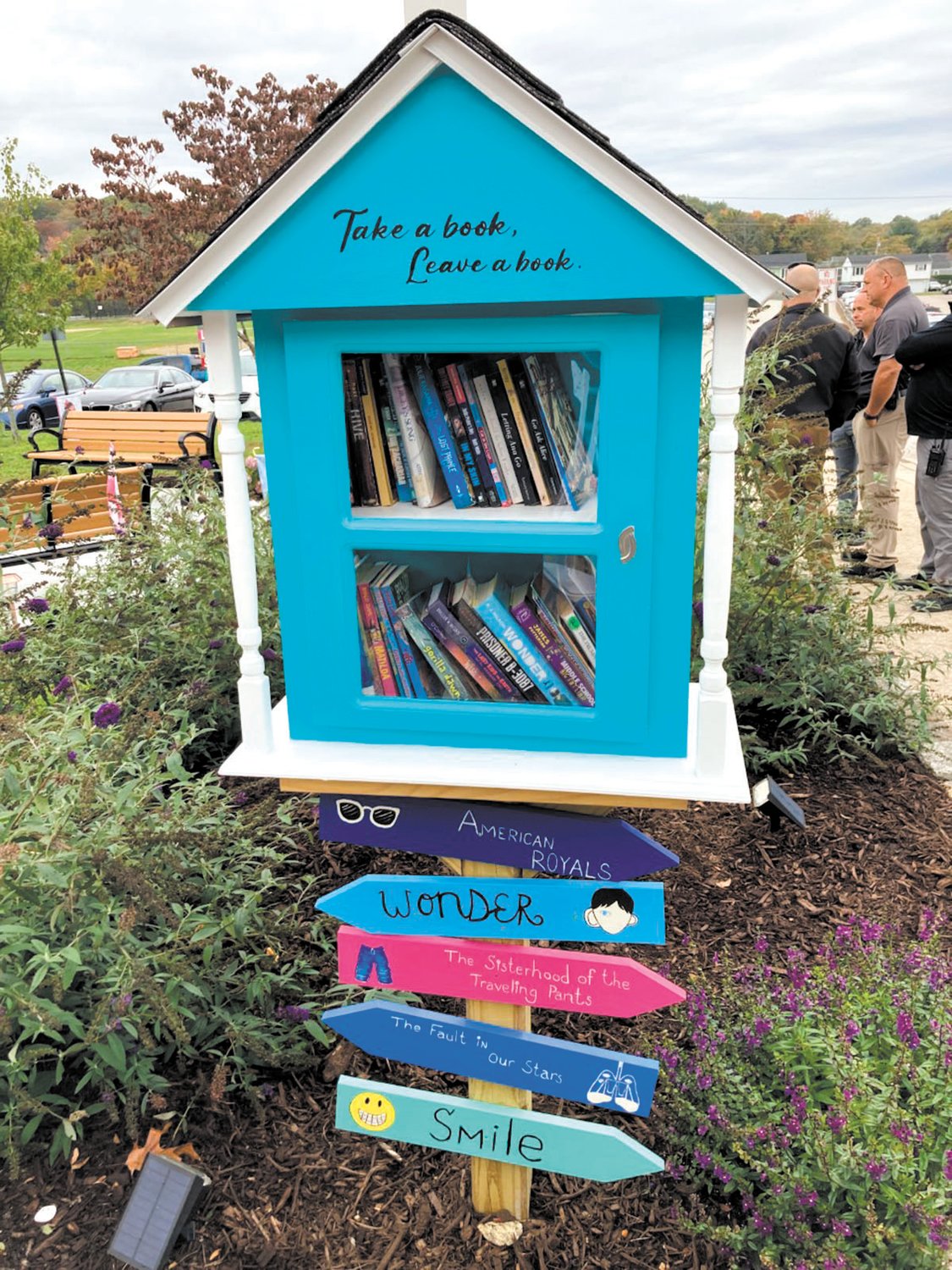 LITTLE LIBRARY: Mia loved reading, so a little library was placed at the learning garden, so students can pick up a book. The library’s post includes wooden arrows listing Mia’s favorite books. (Herald photo)